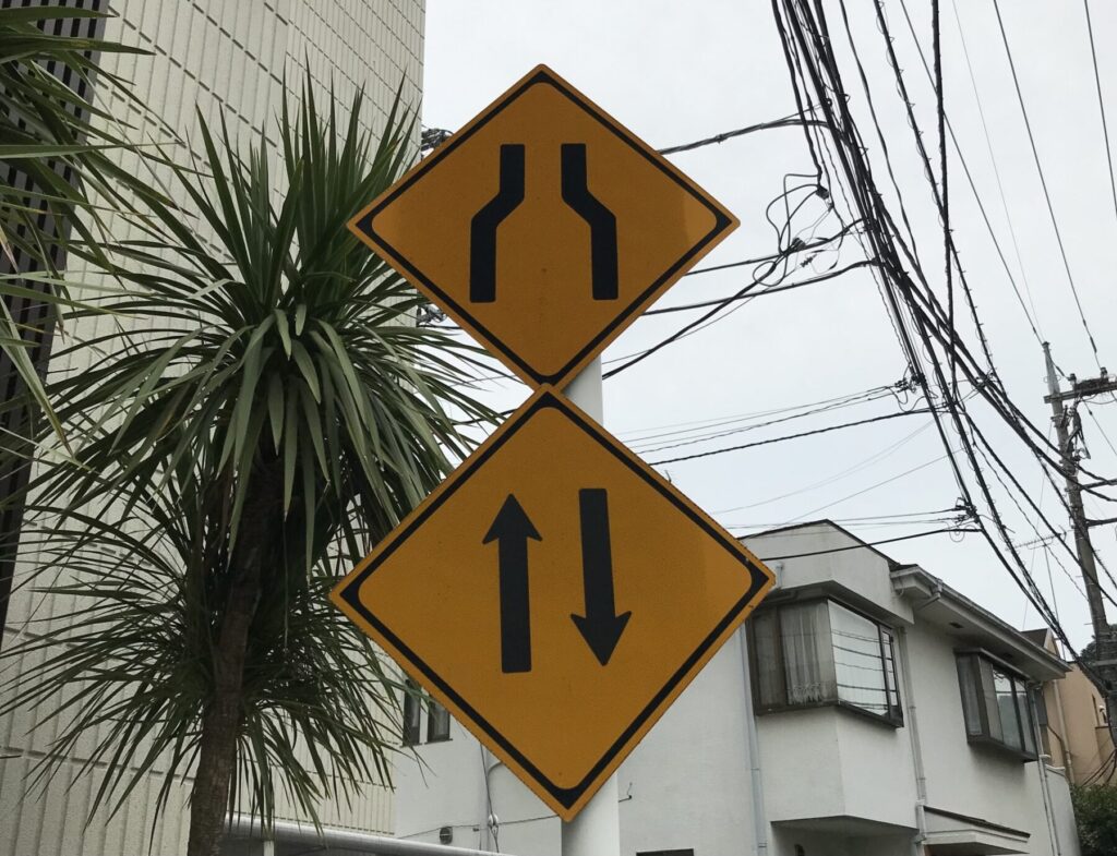 この先、道路が狭くなるという標示