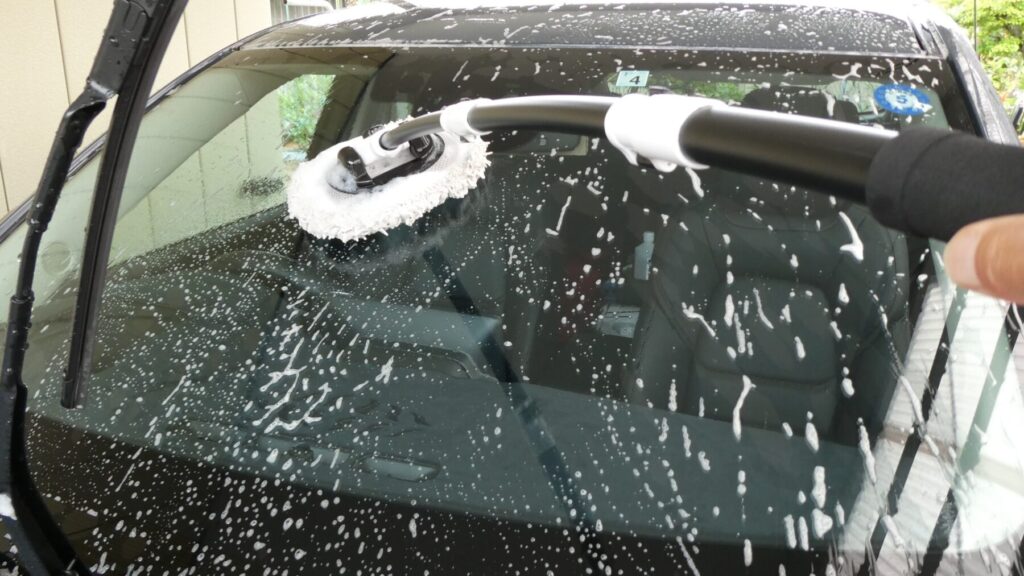 フロントガラスの油膜をブラシで落とす