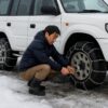 4wdのRV車の4輪にチェーンを装着する男