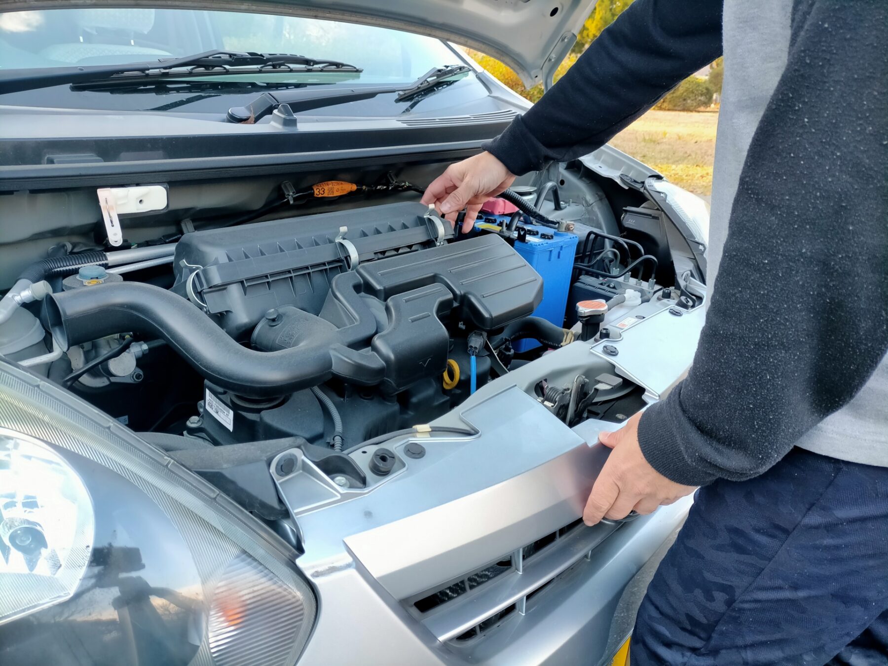 軽自動車のボンネットを開けて点検する