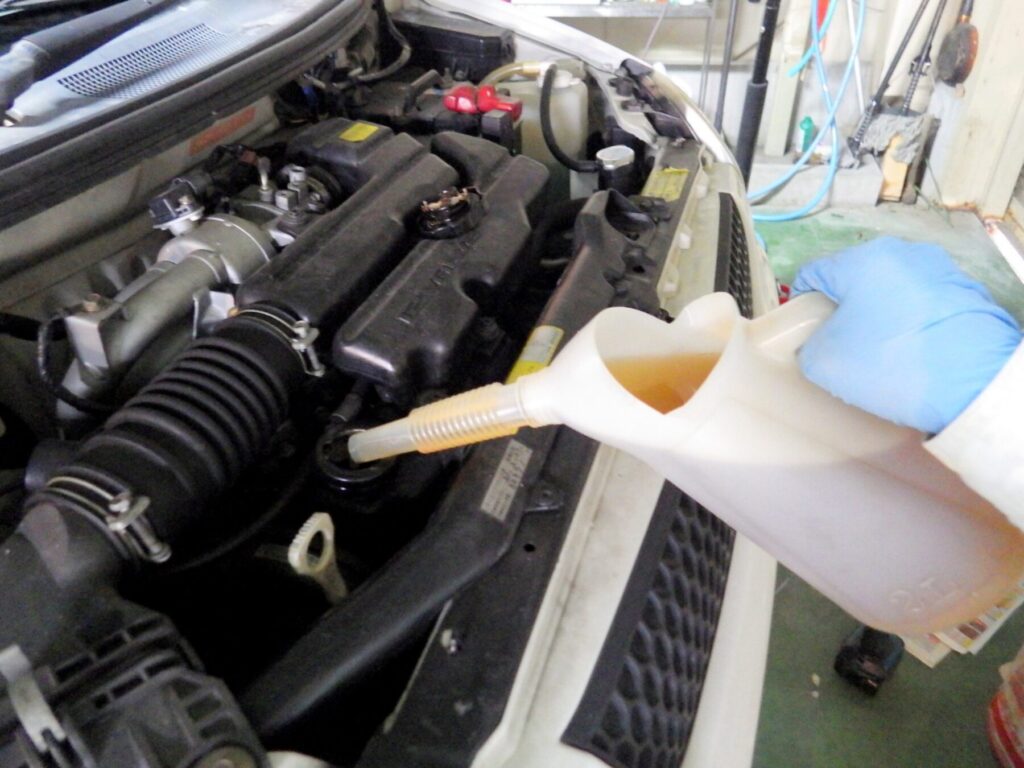 注入器からエンジンオイルをエンジンに入れている