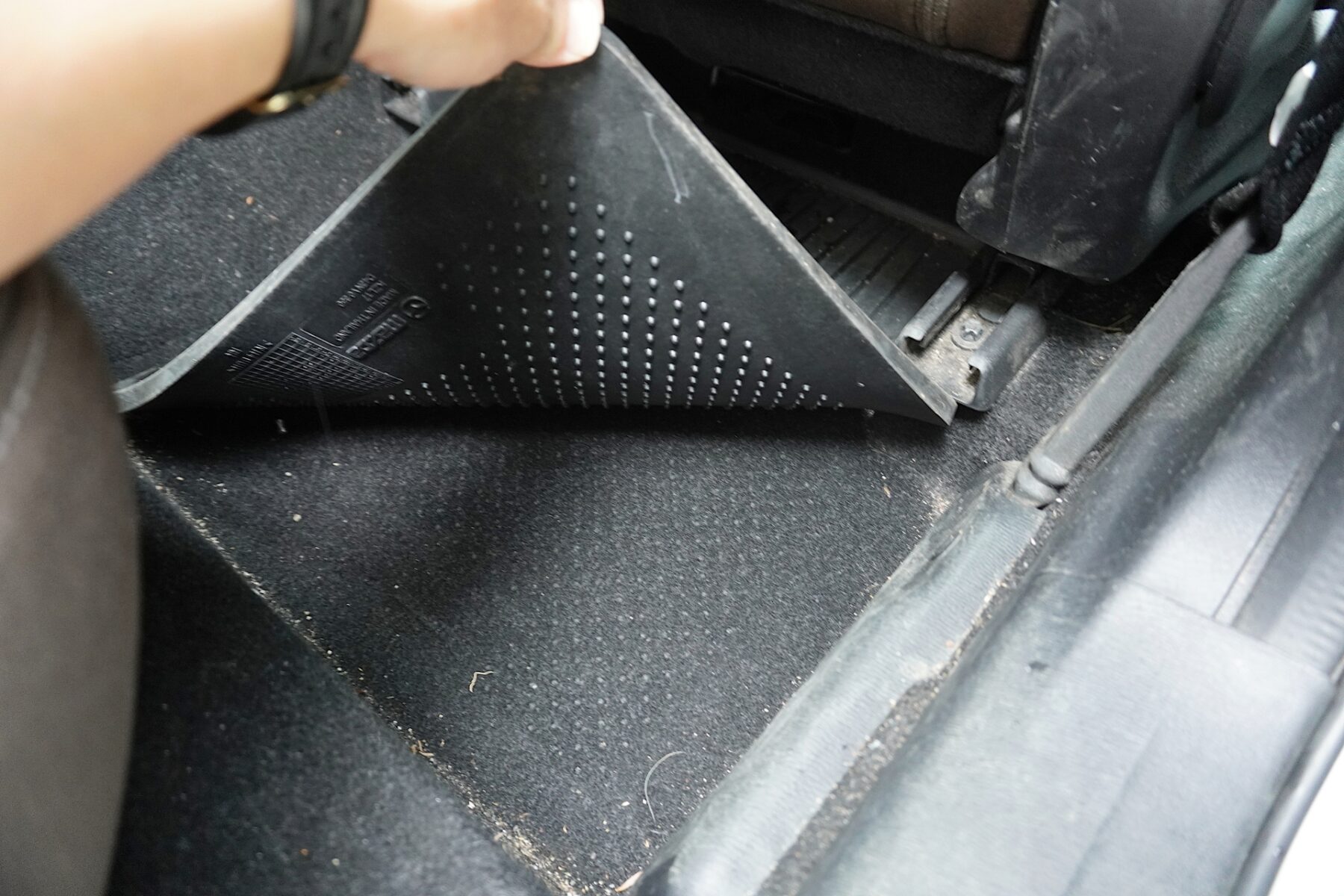 運転席のフロアマットをめくって確認している