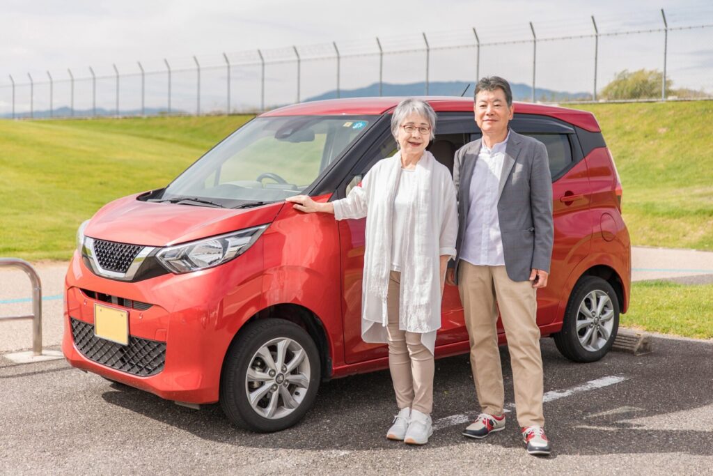 購入した車の前で記念写真を取る老夫婦
