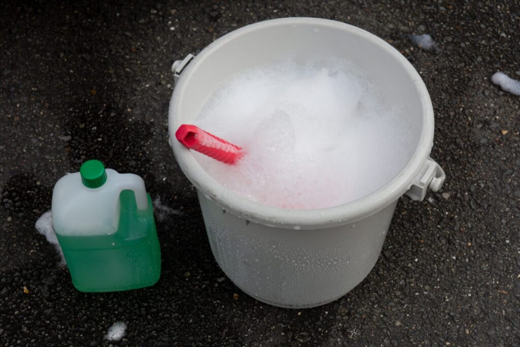 バケツに泡立てた液体で洗車をする