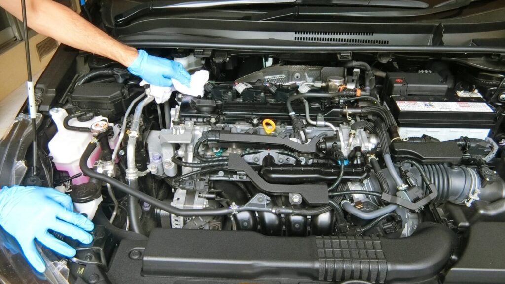 ボンネットを開けてエンジンの調子を見る整備士