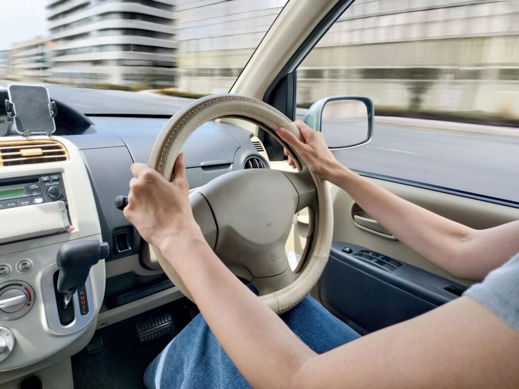 正しい姿勢でハンドルを持ち、車を運転する女