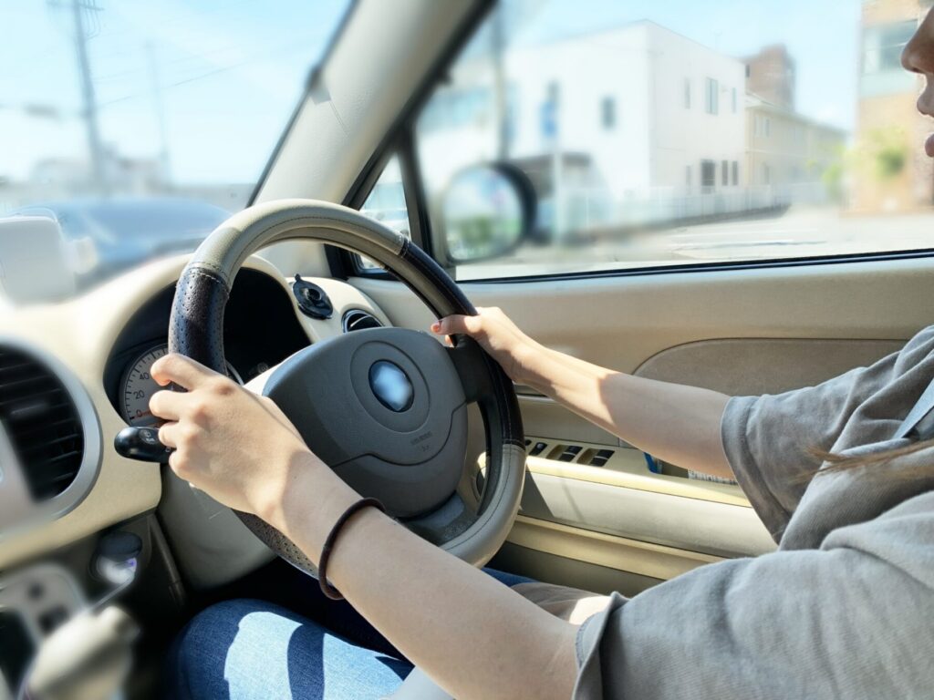 軽自動車のハンドルを握り運転する女