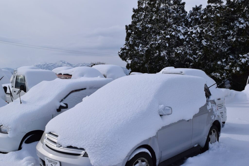 駐車場に止めた車が雪に埋もれている