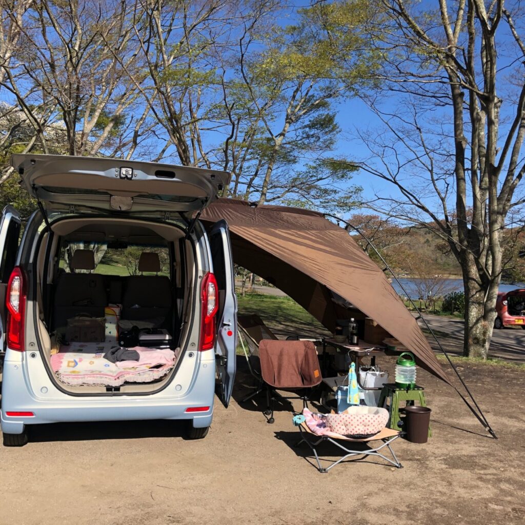 車の横にテントを貼って、休日を楽しんでいる