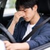 運転に疲れて目のマッサージをする男