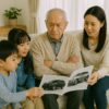 自動車のカタログを見る高齢の男を囲む家族