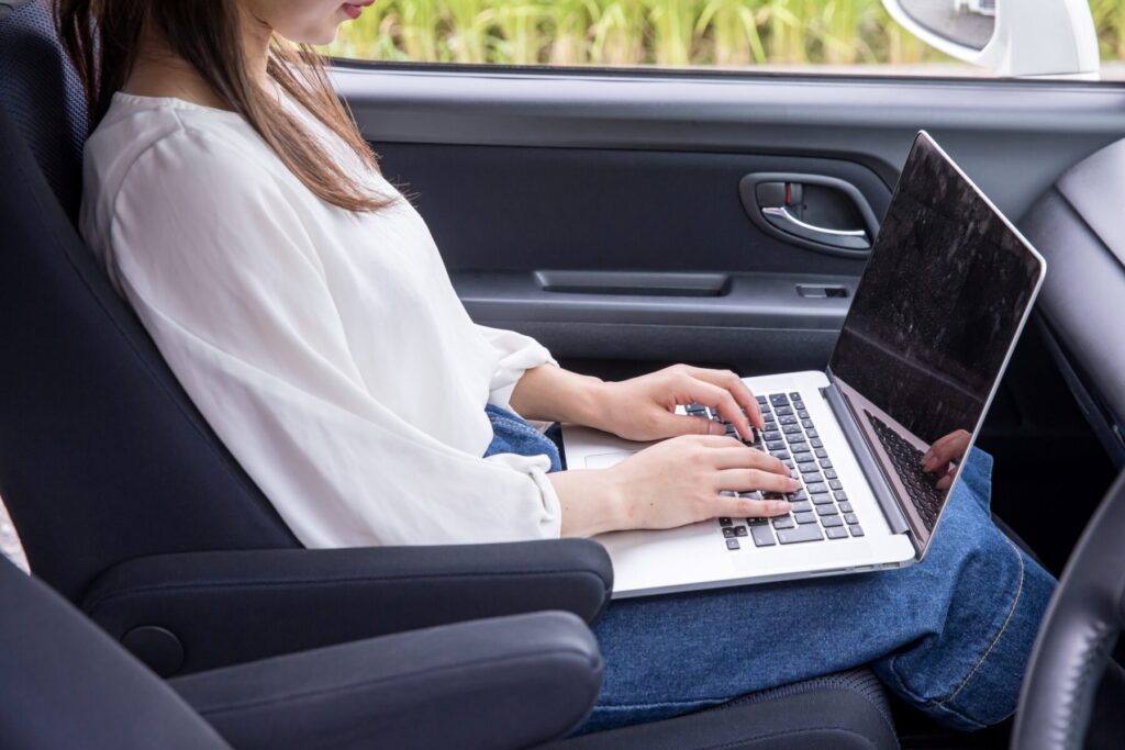 助手席でパソコンを操作する女
