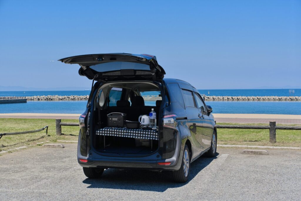 海が見える駐車場に止まるワンボックスカー